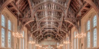 Elegant interior of a historic hall at the University of Manchester, showcasing intricate wooden beams and lighting.