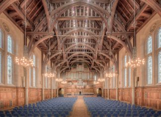 Elegant interior of a historic hall at the University of Manchester, showcasing intricate wooden beams and lighting.