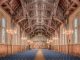 Elegant interior of a historic hall at the University of Manchester, showcasing intricate wooden beams and lighting.