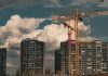 Construction site in Istanbul with cranes and buildings under a dramatic cloudy sky.