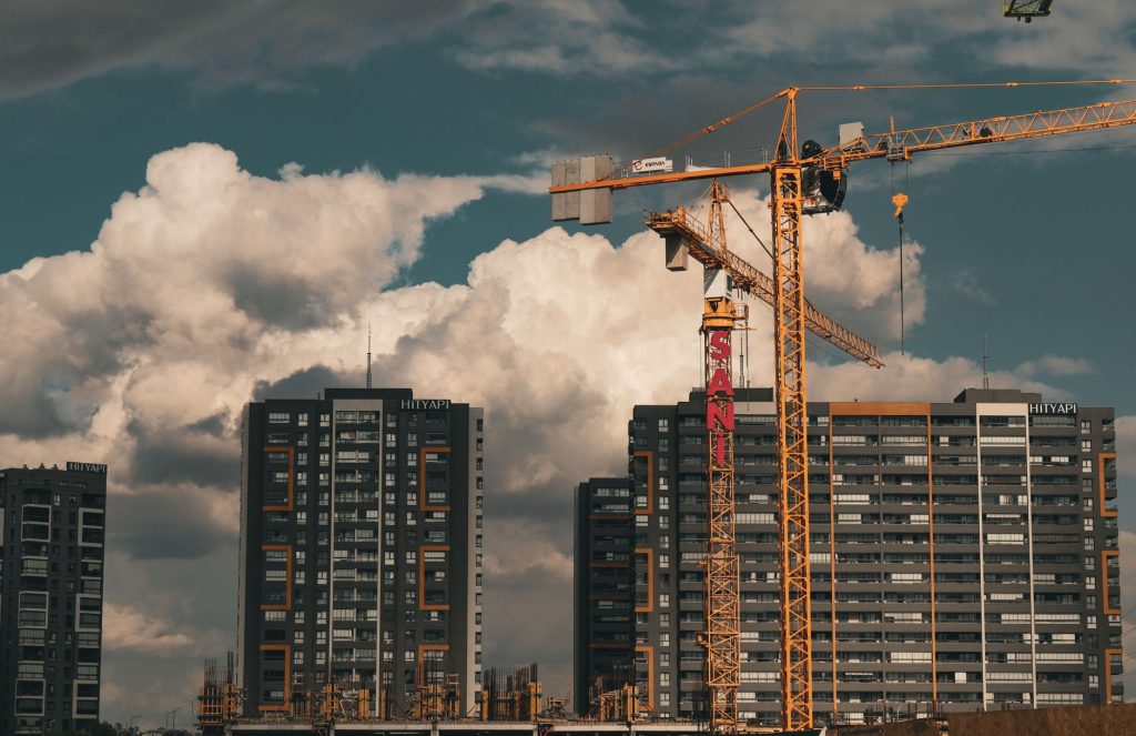 Construction site in Istanbul with cranes and buildings under a dramatic cloudy sky.