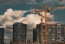Construction site in Istanbul with cranes and buildings under a dramatic cloudy sky.