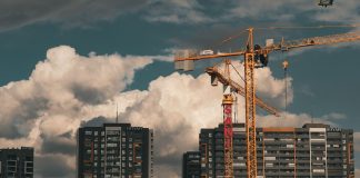 Construction site in Istanbul with cranes and buildings under a dramatic cloudy sky.