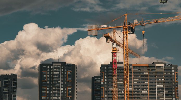 Construction site in Istanbul with cranes and buildings under a dramatic cloudy sky.