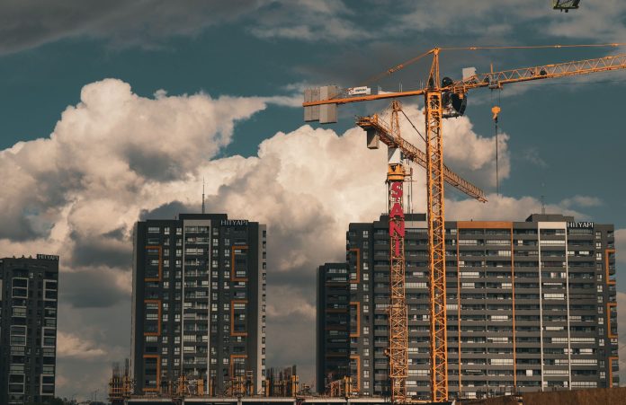 Construction site in Istanbul with cranes and buildings under a dramatic cloudy sky.