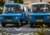 Two retro blue vans parked side by side in a city environment, showcasing classic design.