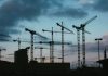 Multiple construction cranes silhouetted against the evening sky, capturing industrial progress.
