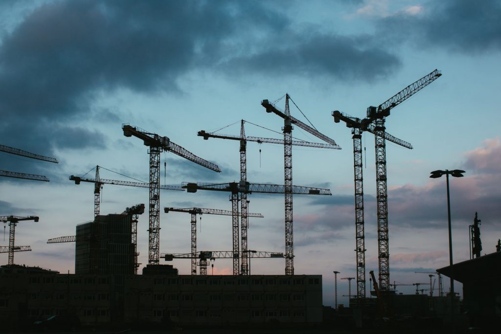 Multiple construction cranes silhouetted against the evening sky, capturing industrial progress.