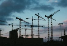Multiple construction cranes silhouetted against the evening sky, capturing industrial progress.