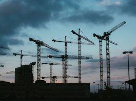 Multiple construction cranes silhouetted against the evening sky, capturing industrial progress.