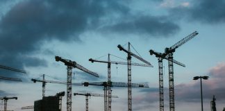 Multiple construction cranes silhouetted against the evening sky, capturing industrial progress.