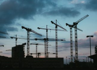 Multiple construction cranes silhouetted against the evening sky, capturing industrial progress.