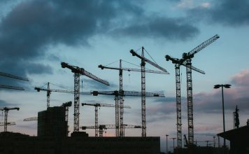 Multiple construction cranes silhouetted against the evening sky, capturing industrial progress.