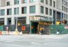 City streetscape featuring a building under construction with closed sidewalk signage.