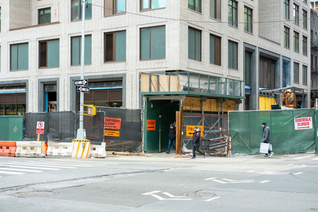 City streetscape featuring a building under construction with closed sidewalk signage.