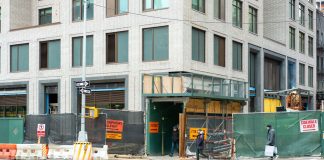 City streetscape featuring a building under construction with closed sidewalk signage.