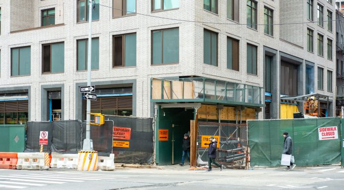 City streetscape featuring a building under construction with closed sidewalk signage.