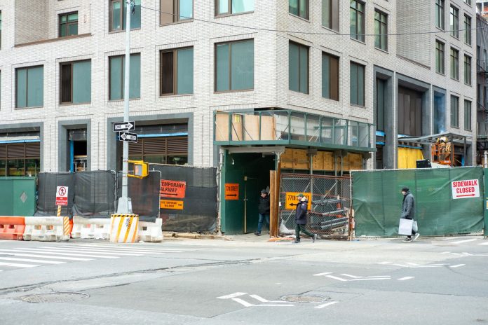 breaking-joboken-cafe-faces-construction-challenge City streetscape featuring a building under construction with closed sidewalk signage.