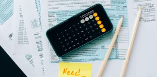Top view of financial papers with a calculator, pencils, and a note saying 'Need help?' indicating tax or accounting assistance.