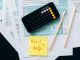 Top view of financial papers with a calculator, pencils, and a note saying 'Need help?' indicating tax or accounting assistance.