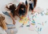 Group of women designing artistic placards with colorful materials.