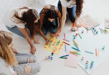 Group of women designing artistic placards with colorful materials.