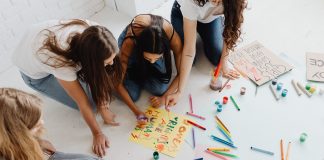Group of women designing artistic placards with colorful materials.