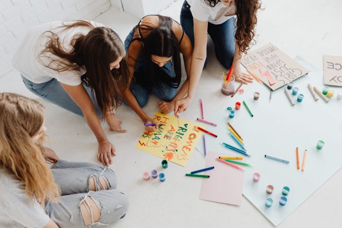 breaking-newark-community-art-project-the-golden-l Group of women designing artistic placards with colorful materials.