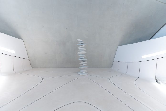 A minimalist and futuristic interior featuring stacked stones and white walls.