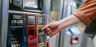 Close-up of a person using a metro card machine for public transport payment indoors.