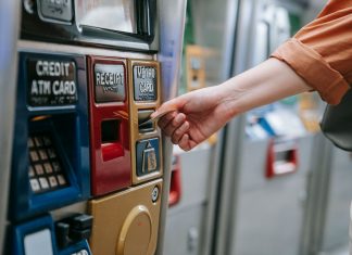 Close-up of a person using a metro card machine for public transport payment indoors.