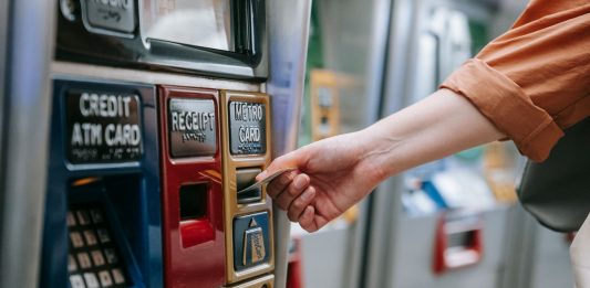 BREAKING: PATH Phases Out SmartLink Cards September 1 Close-up of a person using a metro card machine for public transport payment indoors.