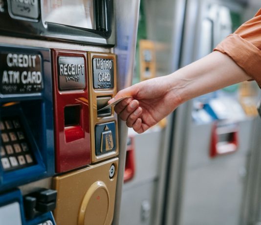 Close-up of a person using a metro card machine for public transport payment indoors.