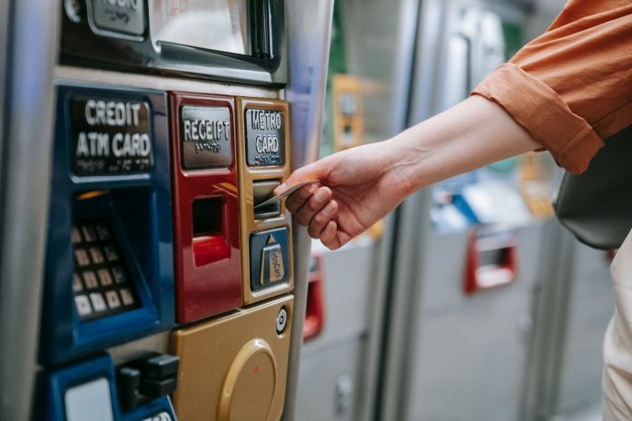 Close-up of a person using a metro card machine for public transport payment indoors.