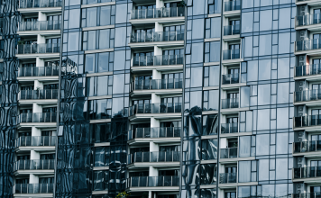 High-rise building with glass facade reflecting surroundings.