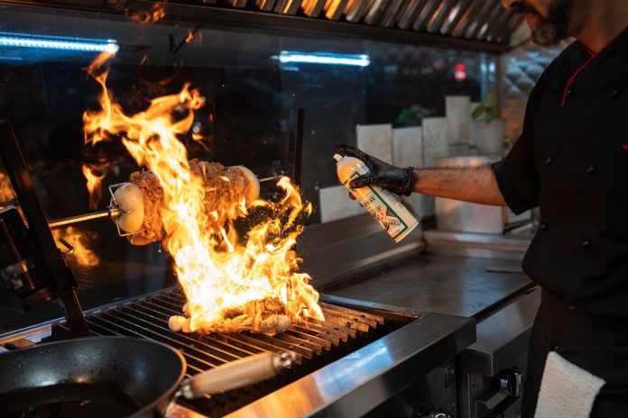 breaking-viral-food-truck-the-colonial-grill-opens Chef uses a culinary torch to ignite a flaming grill indoors, showcasing dynamic cooking.