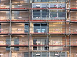 Scaffolding covers an urban building facade, capturing a construction site in detail.