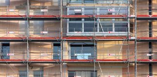 Scaffolding covers an urban building facade, capturing a construction site in detail.