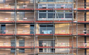 Scaffolding covers an urban building facade, capturing a construction site in detail.