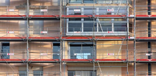 Brennan Courthouse HVAC Fix Delayed Again as County, City Spar Scaffolding covers an urban building facade, capturing a construction site in detail.