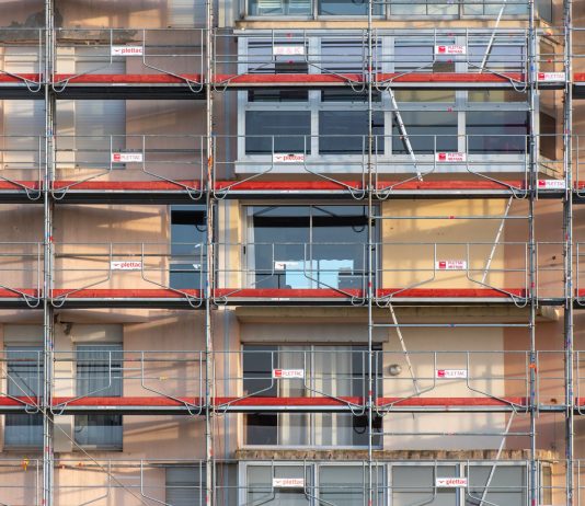 Scaffolding covers an urban building facade, capturing a construction site in detail.
