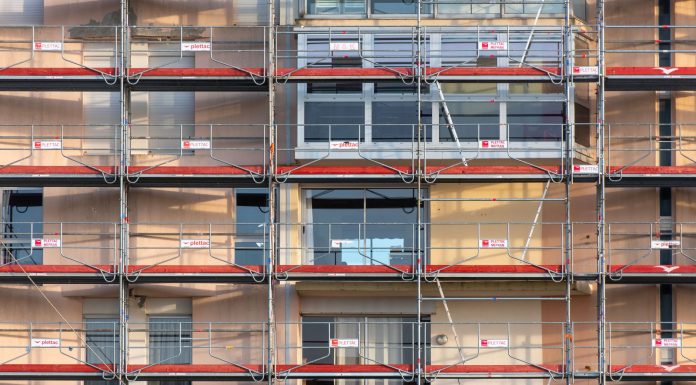 Brennan Courthouse HVAC Fix Delayed Again as County, City Spar Scaffolding covers an urban building facade, capturing a construction site in detail.