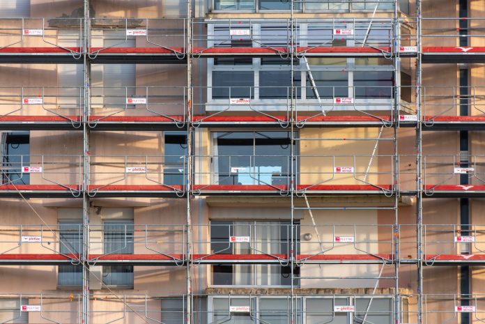 Scaffolding covers an urban building facade, capturing a construction site in detail.