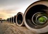 Massive concrete pipes aligned at a construction site during sunset, showcasing an industrial landscape.