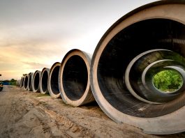 Massive concrete pipes aligned at a construction site during sunset, showcasing an industrial landscape.