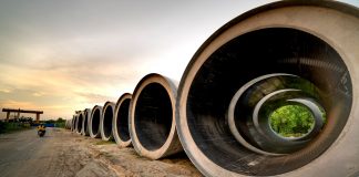 Massive concrete pipes aligned at a construction site during sunset, showcasing an industrial landscape.