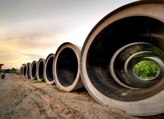 Massive concrete pipes aligned at a construction site during sunset, showcasing an industrial landscape.
