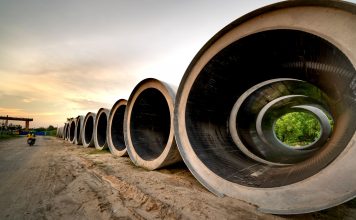 Massive concrete pipes aligned at a construction site during sunset, showcasing an industrial landscape.