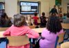 Students attentively watching a lesson on a smart board in a colorful Dutch classroom.