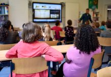 Students attentively watching a lesson on a smart board in a colorful Dutch classroom.
